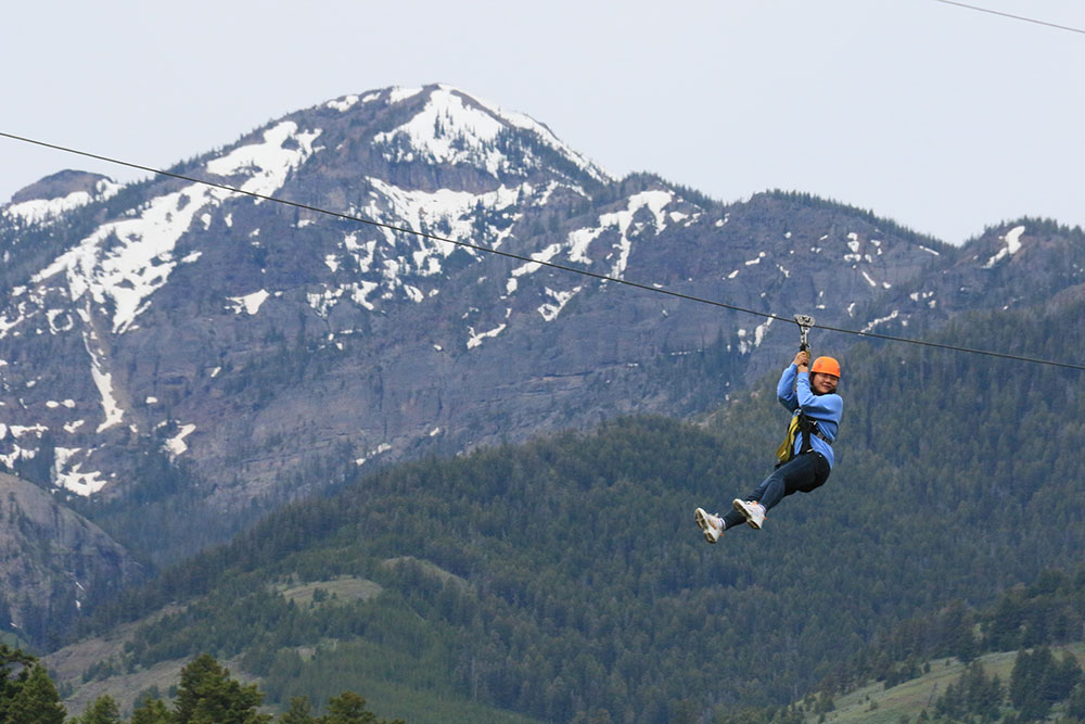 A person ziplining with the mountains in the background.